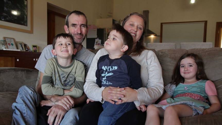 Mark and Holly Jessop on their couch with their three children, Jack, Riley and Pearl.