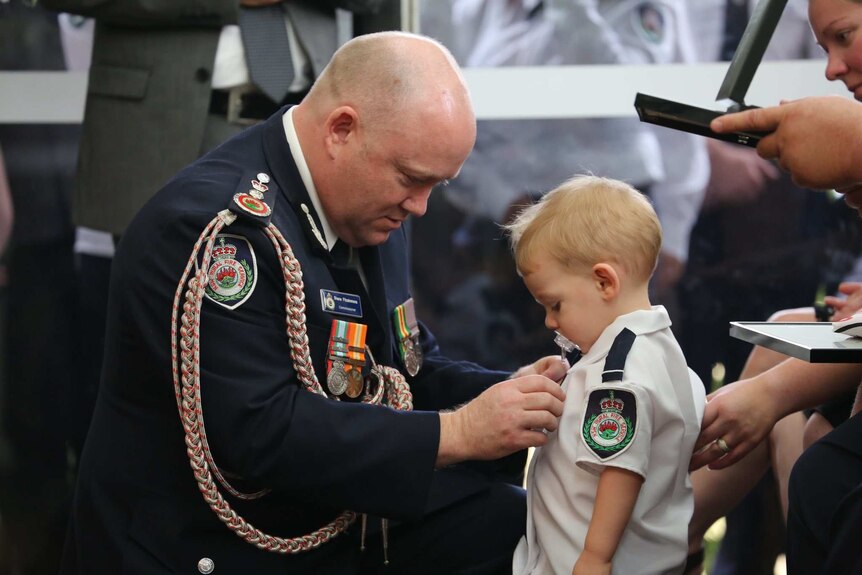 man pinning medal on toddler