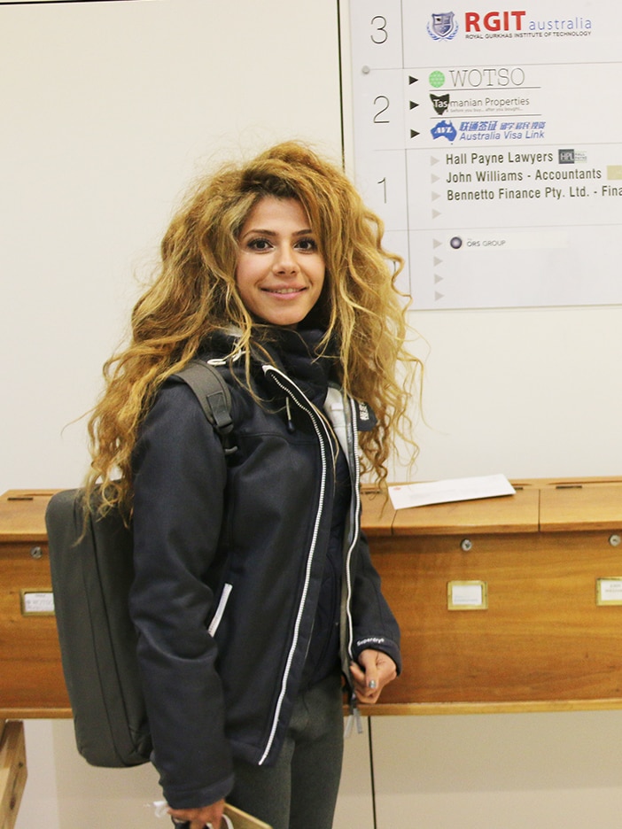 A young woman with luxurious hair stands in a hallway.