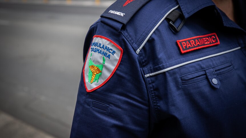 Sign on a blue uniform reads: Ambulance Tasmania paramedic