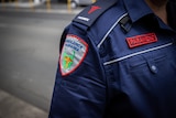 Sign on a blue uniform reads: Ambulance Tasmania paramedic