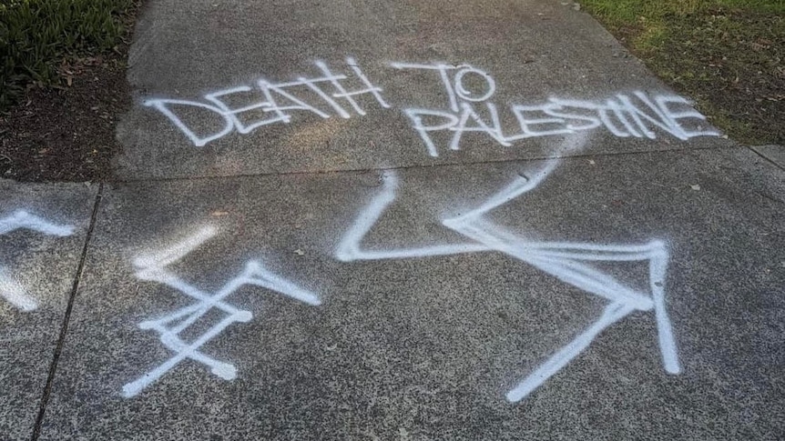 Death to Palestine and swastikas are spray painted on a grey driveway.