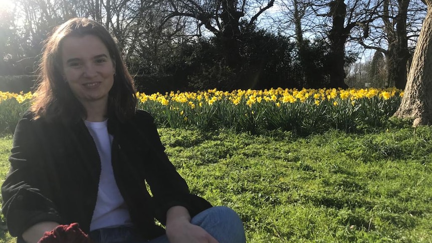 Girl sitting on grass with daffodils behind