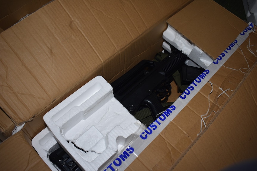 Black semi-automatic firearms in foam packaging in a box.
