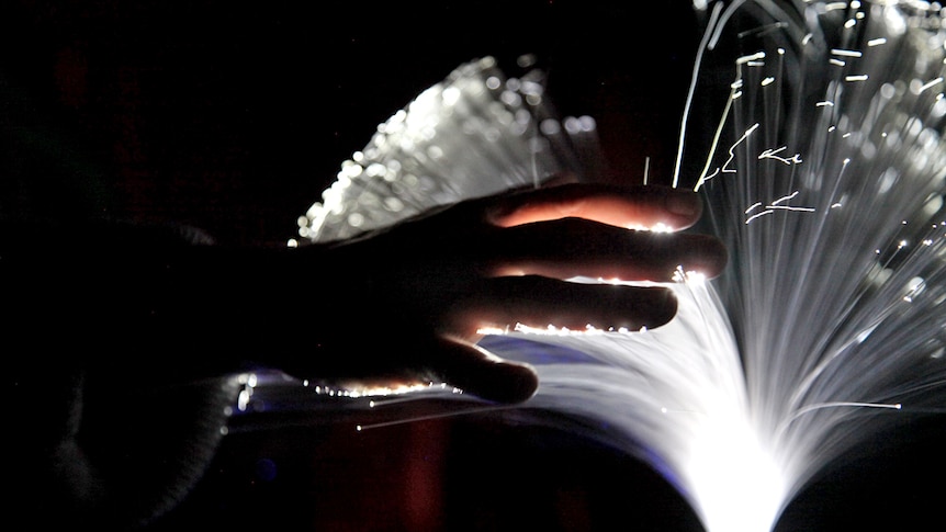 A hand touches bright fibre optic cables