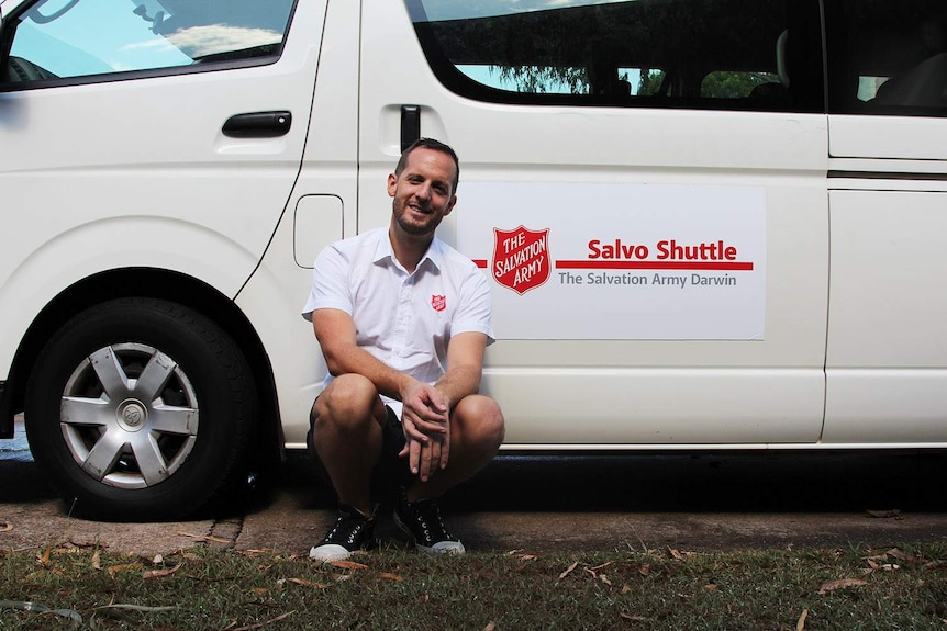 A man sitting in front of a white shuttle bus