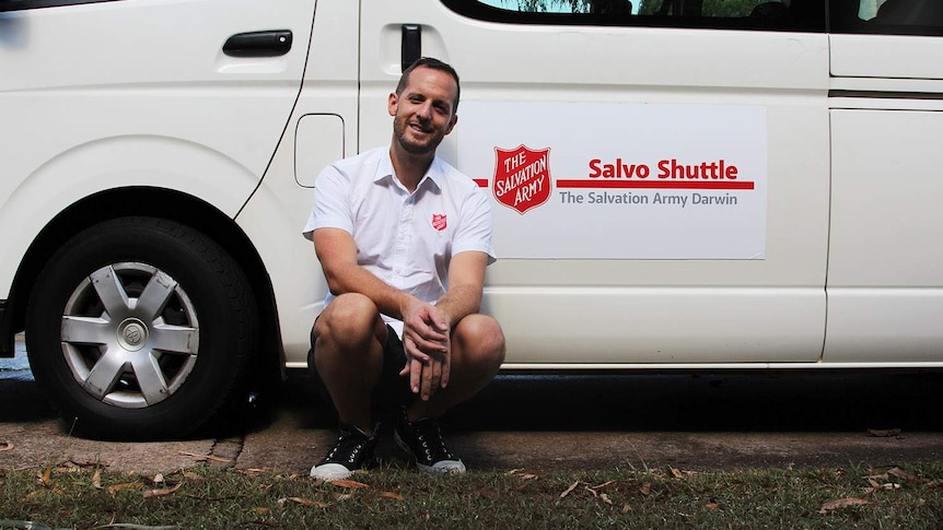 A man sitting in front of a white shuttle bus