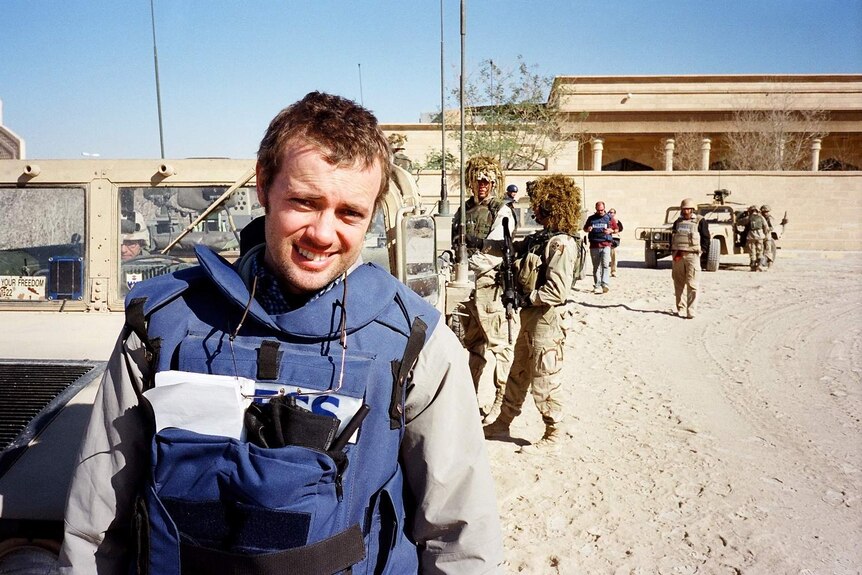 Dean Yates stands in front of army vehicles in Tikrit, November 2003.