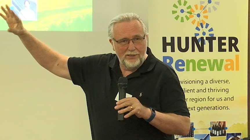 A man holding a microphone in front of a presentation.