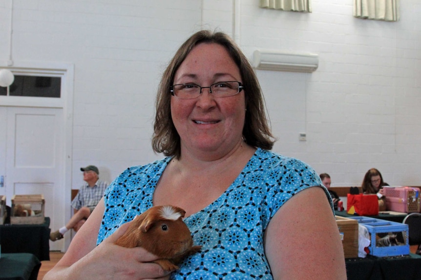 A woman holding an orange guinea pig
