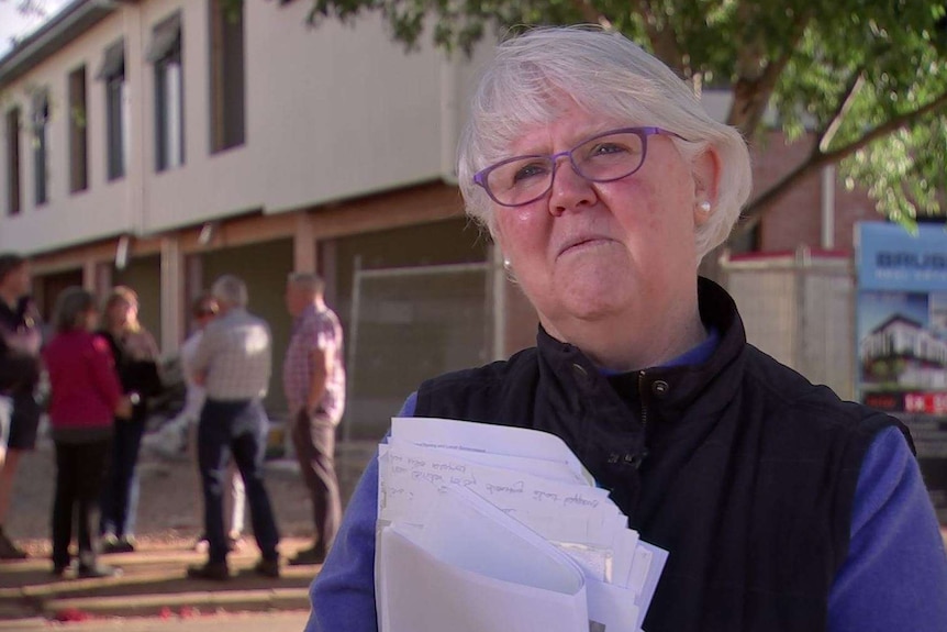 A woman stands in front of a new housing development