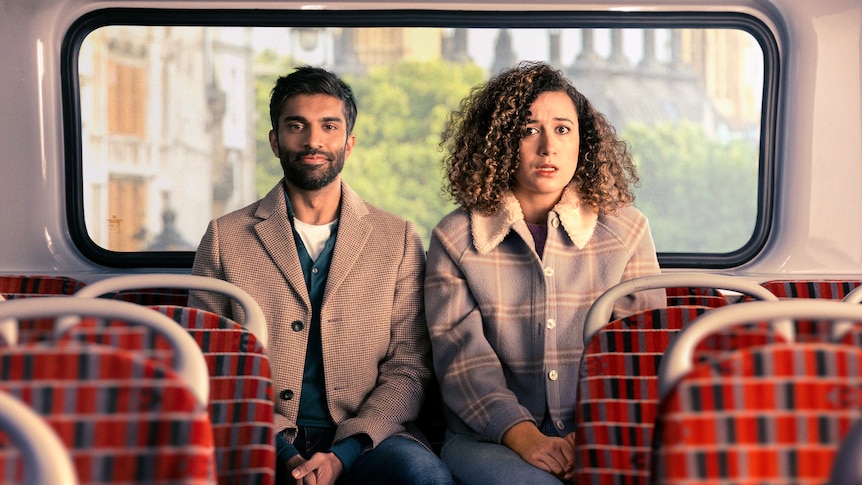 Nikesh Patel is sat on the left of the upper deck of a bus in London, Rose Matafeo is on the right with a shocked expression.