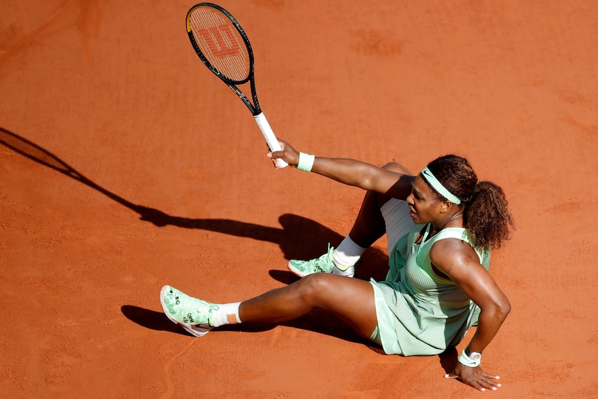 Serena Williams sits down on a clay tennis court at Roland Garros.