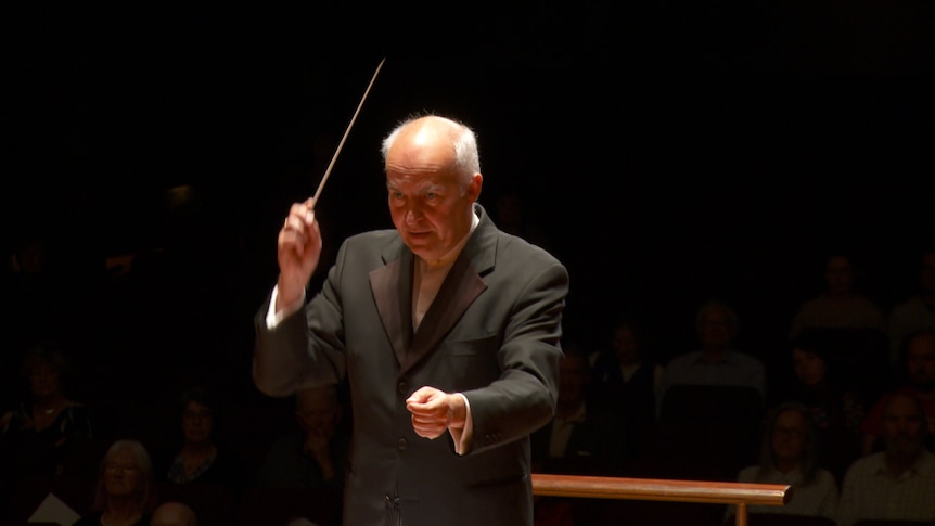 Johannes Fritzsch conducting in a back suit.