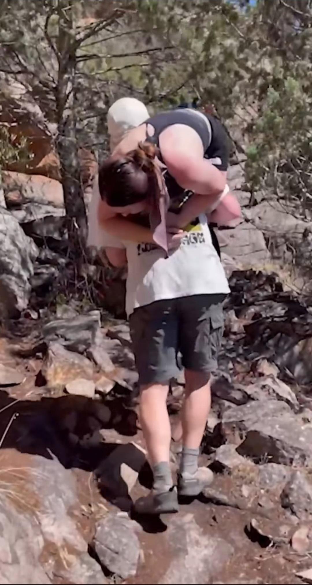 Um homem carrega Sarah Larcombe pelo mato.