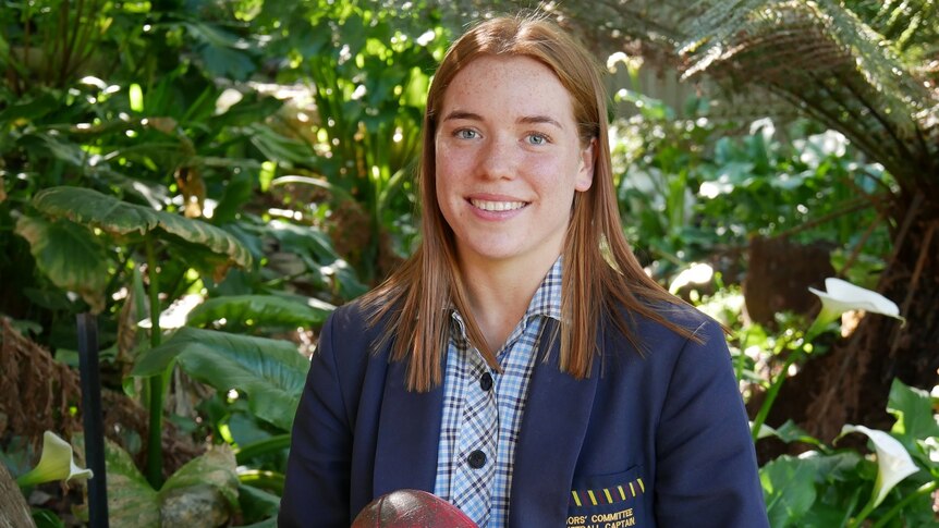Mia King, aspiring Tasmanian AFLW footballer, holds a football.