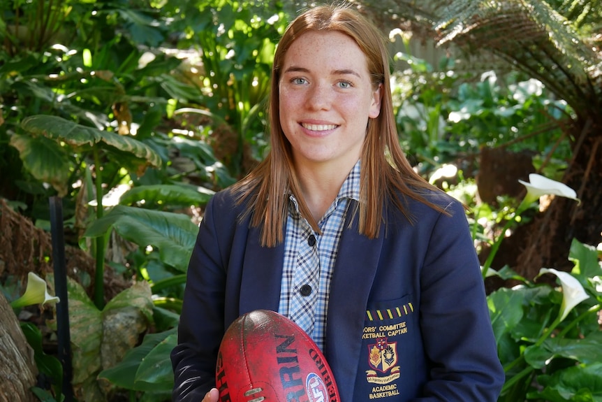 Mia King, aspiring Tasmanian AFLW footballer, holds a football.