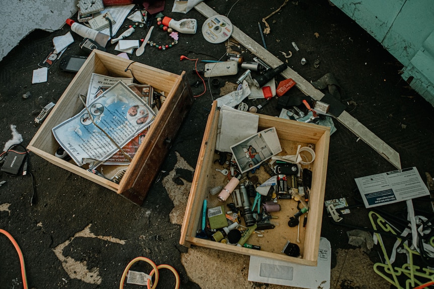 Two drawers with photos, mementos, and other belongings sit on the flood-damaged floor.