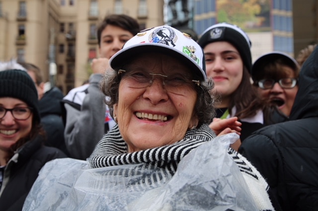 A woman smiles while wearing a Collingwood cap at the AFL grand final parade.