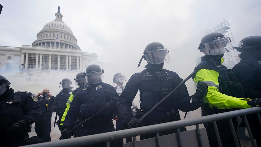 Police stand in front of the Capitol in Washington in a cloud of gas.