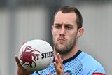 Isaah Yeo in blue NSW training attire catches the ball in front of his face.