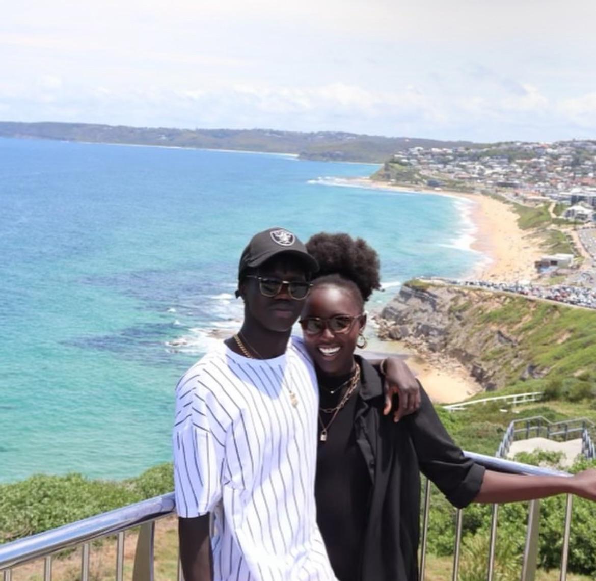 Valentino Yuel and his partner Jacki Tut above a beach in Newcastle