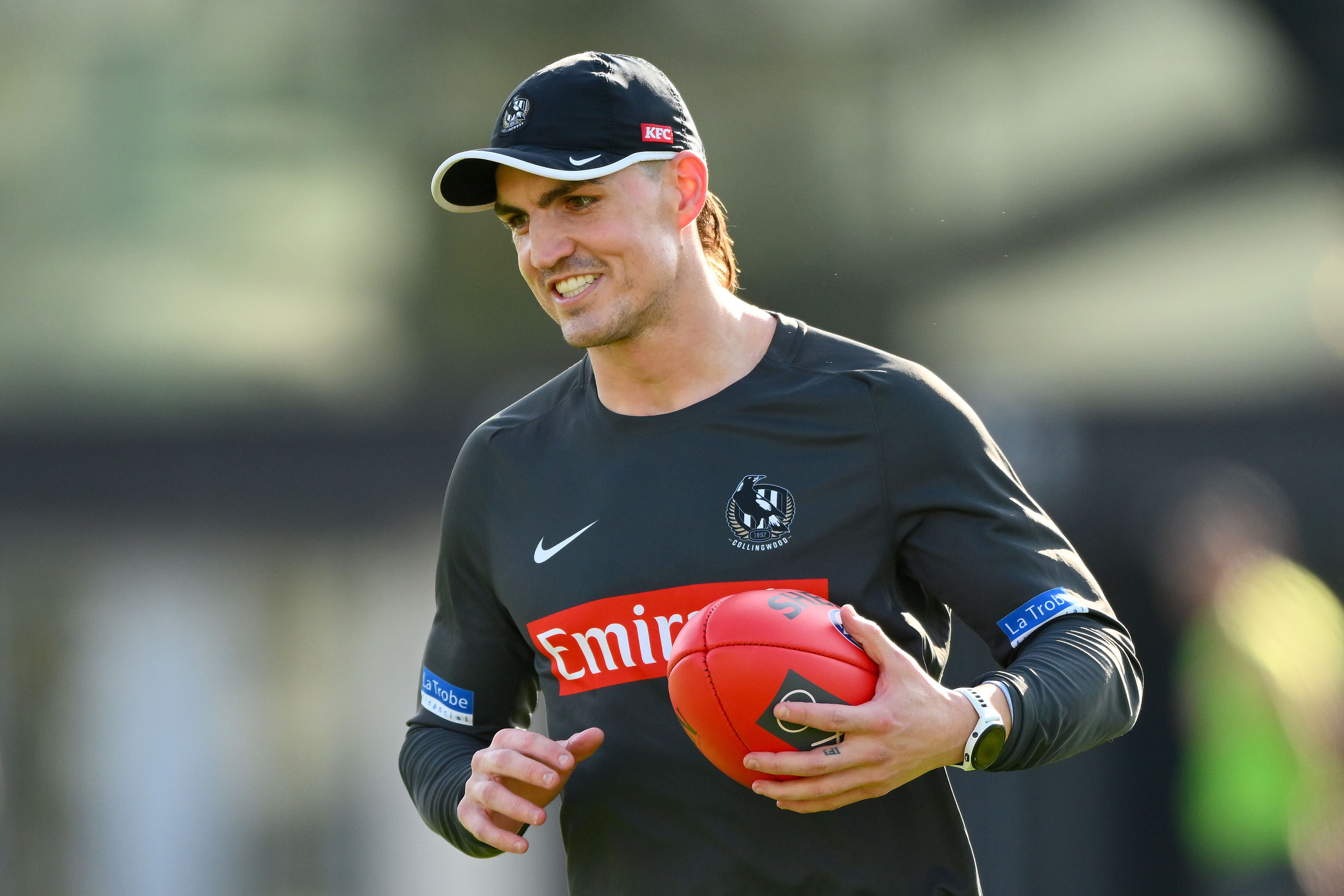 Brayden Maynard smiles while holding a football at Collingwood training