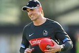 Brayden Maynard smiles while holding a football at Collingwood training