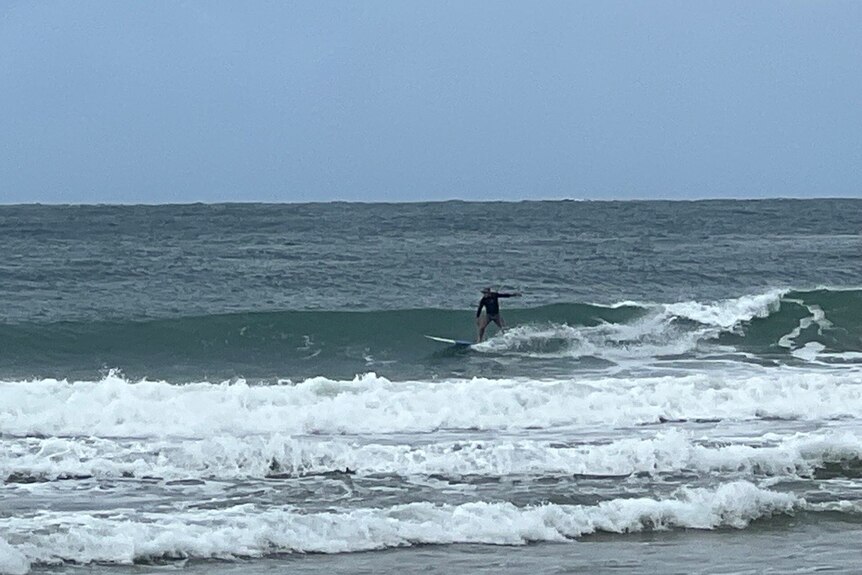 Man catching waves with surfboard at Park Beach Coffs Harbor 