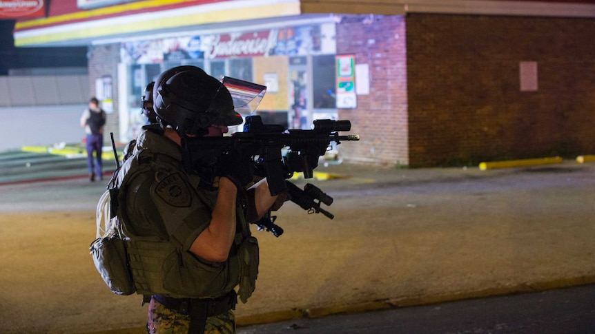 Police officer holding aiming a weapon in Ferguson, Missouri.