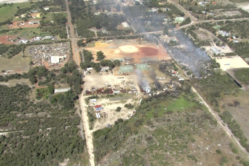 An aerial image of a small amount of smoke billowing over non-residential structures