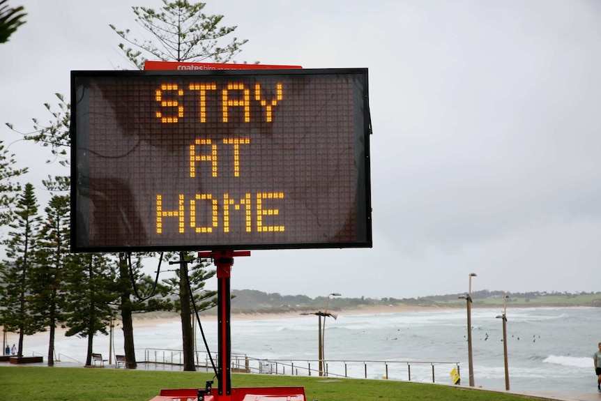 a stay at home sign on a beach front