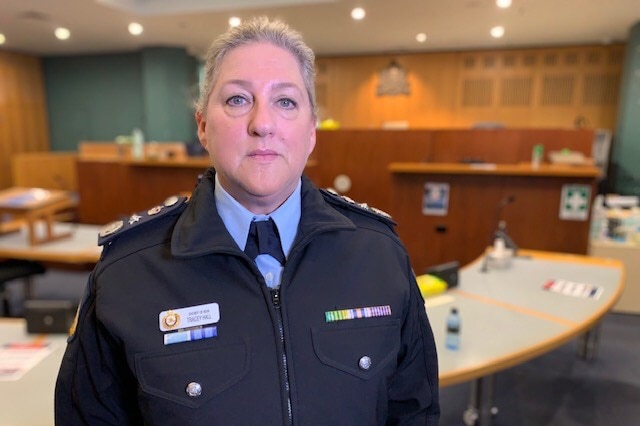 A woman in a uniform stands inside a courtroom.