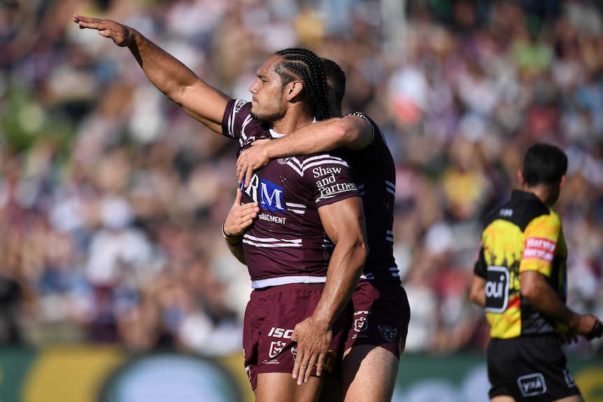 Martin Taupau makes a salute with his right arm as he is hugged by a teammate after scoring a try.