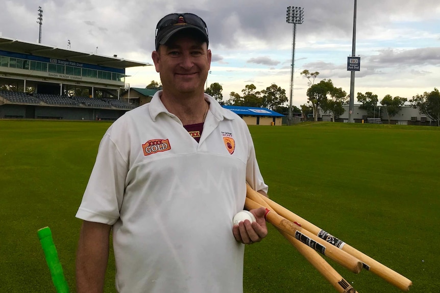 Man with cricket stumps bat and ball