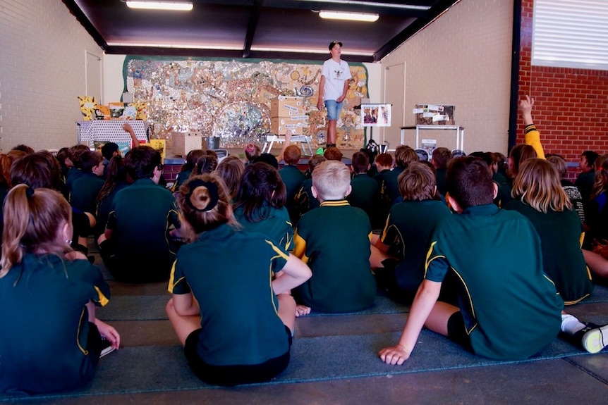 Students sitting in covered assembly area watching a bee presentation.