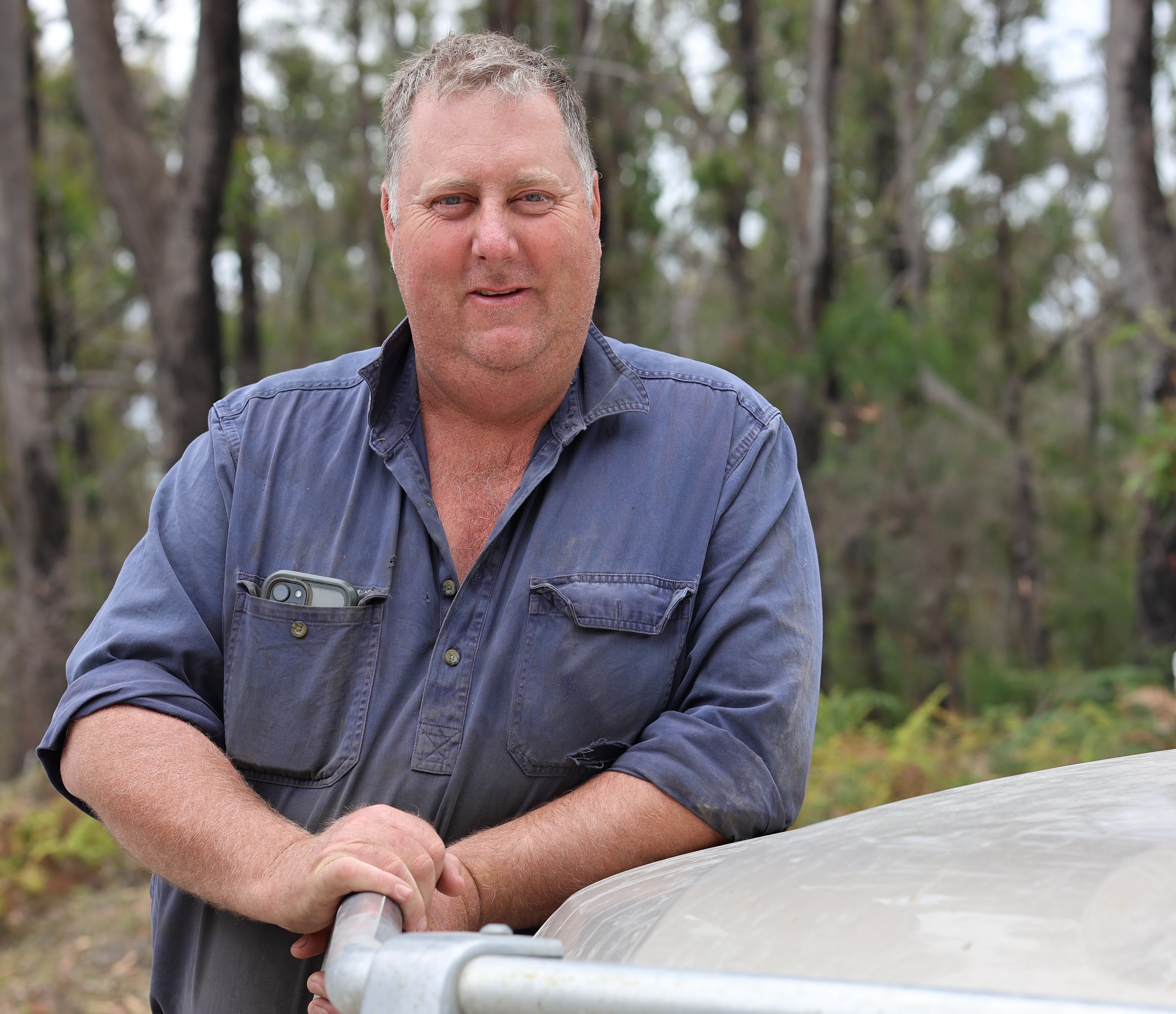 tree species a man leans against a vehicle in front of a bush reserve