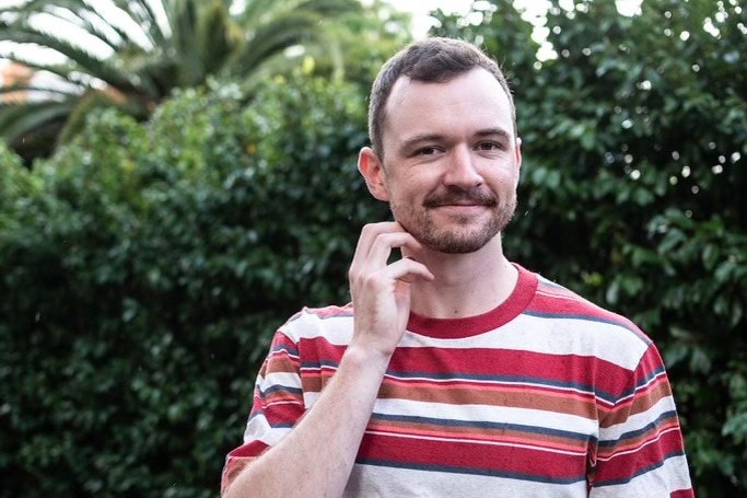 Stephen Grace smiles while wearing a striped shirt.