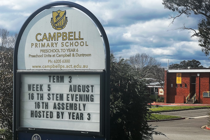 A primary school with a noticeboard out front that reads "Campbell Primary School".