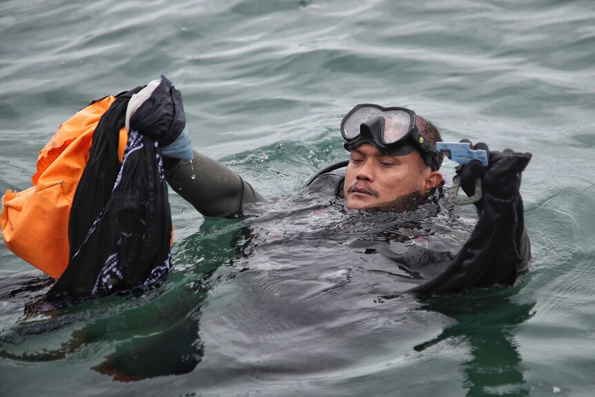 An Indonesian Navy diver shows debris recovered from the water