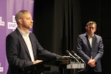 Brett Sutton speaks at a press conference while Premier Daniel Andrews looks on.