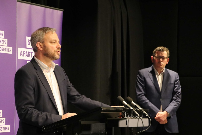 Brett Sutton speaks at a press conference while Premier Daniel Andrews looks on.