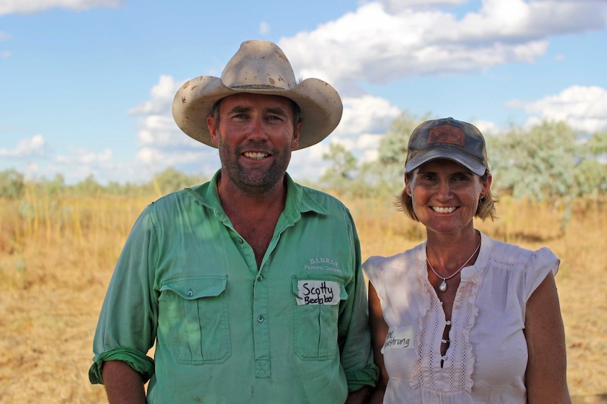 a man and a woman stand in a paddock