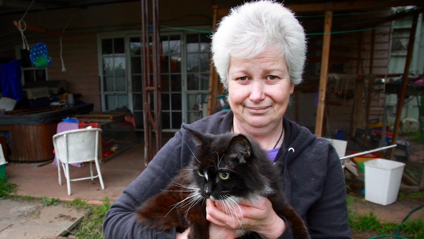 Cat whisperer Yvette Harper standing outside her home holding a cat.