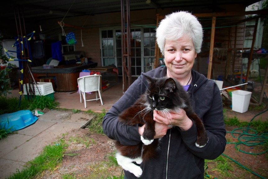 Cat whisperer Yvette Harper standing outside her home holding a cat.