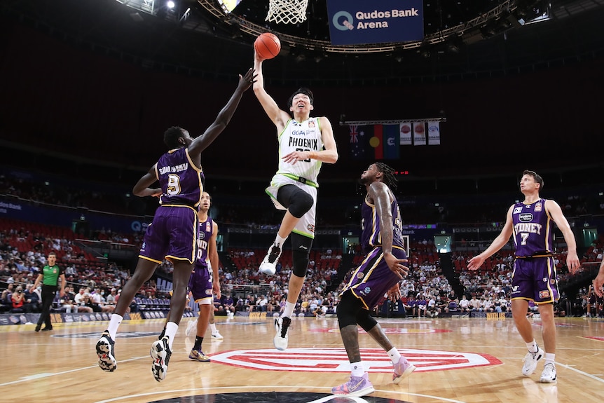 A basketballer launches himself towards the ring.