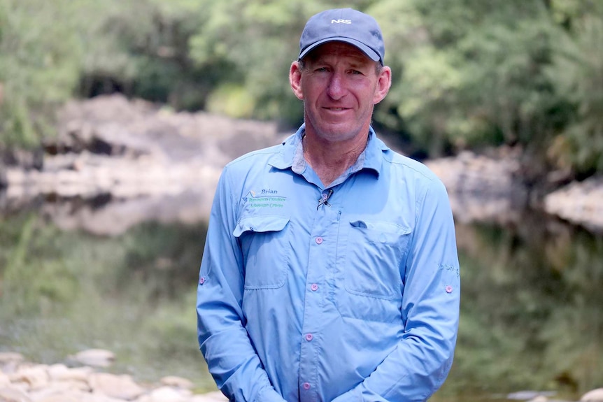 A man stands in front of a location that should be suitable for white water rafting.