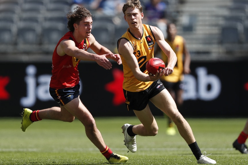 Matthew Johnson gets a handball away while an opponent looks to tackle him