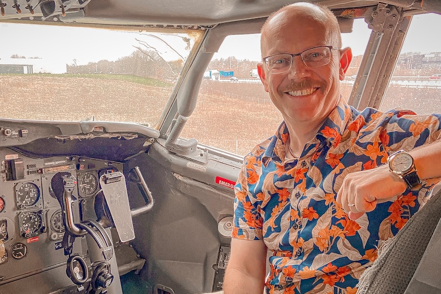 Man smiling in cockpit of a plane.