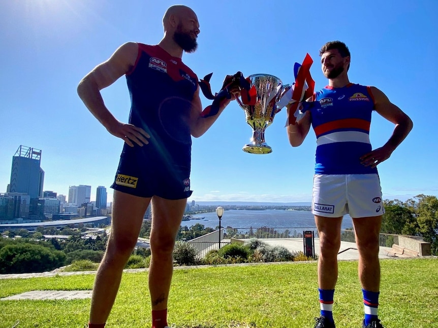Demons captain Max Gawn and Bulldogs captain Marcus Bontempelli face each other while holding the cup